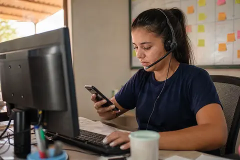 Atendente de uma empresa de perfuração de poços falando com clientes pelo WhatsApp no computador e no celular