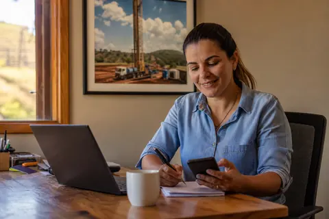 Empresária de uma empresa de perfuração de poços preparando um orçamento no notebook e no celular